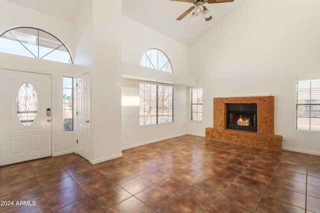 tiled foyer entrance with a high end fireplace, high vaulted ceiling, and ceiling fan