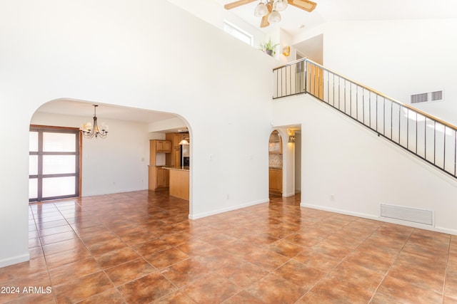 unfurnished living room featuring a high ceiling and ceiling fan with notable chandelier