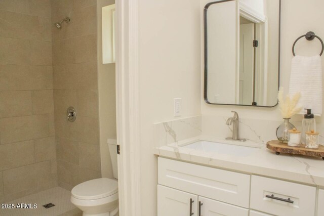 bathroom with vanity, toilet, and a tile shower