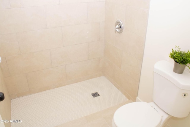 bathroom featuring a tile shower and toilet