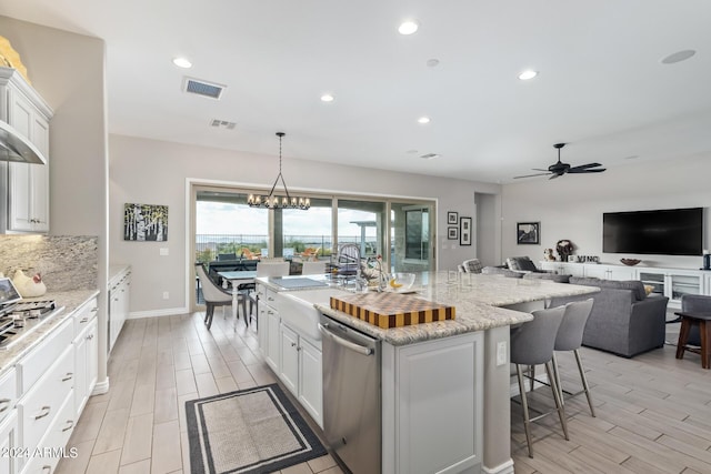 kitchen with white cabinets, wood tiled floor, a breakfast bar area, and stainless steel appliances