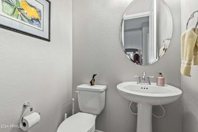 half bathroom with a textured wall and toilet