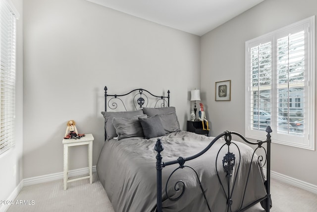 carpeted bedroom featuring multiple windows and baseboards