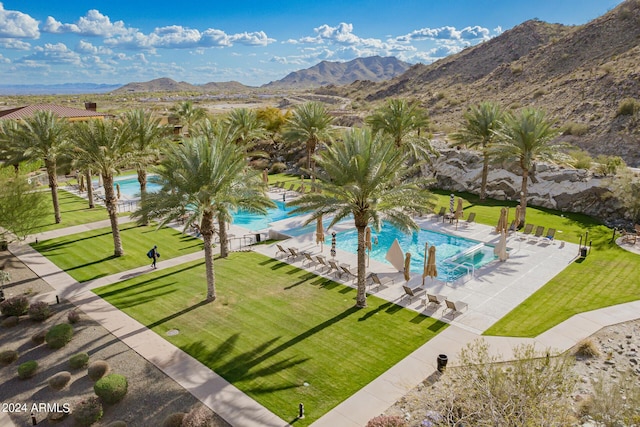 pool with a patio area, a mountain view, and a yard