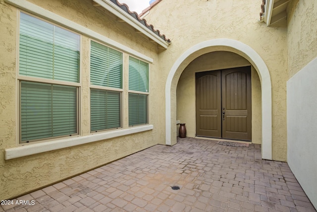 property entrance with a tile roof, a patio, and stucco siding