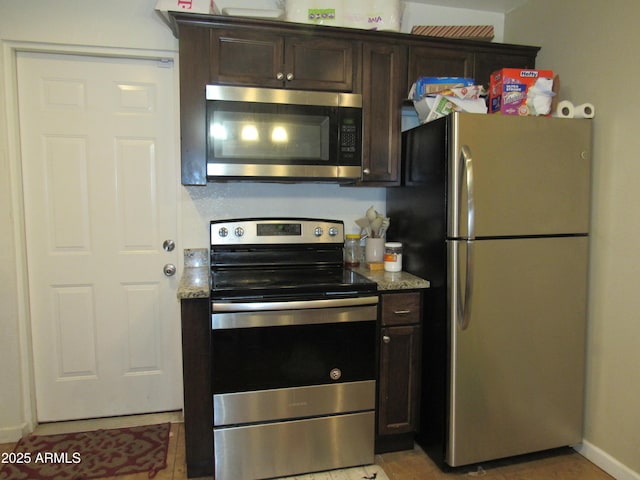 kitchen featuring dark brown cabinetry, light stone counters, stainless steel appliances, baseboards, and light tile patterned floors
