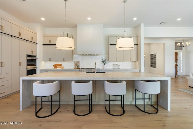 kitchen featuring pendant lighting, a spacious island, stainless steel double oven, and a kitchen breakfast bar