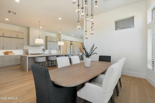 dining room with sink, a wealth of natural light, and light hardwood / wood-style flooring