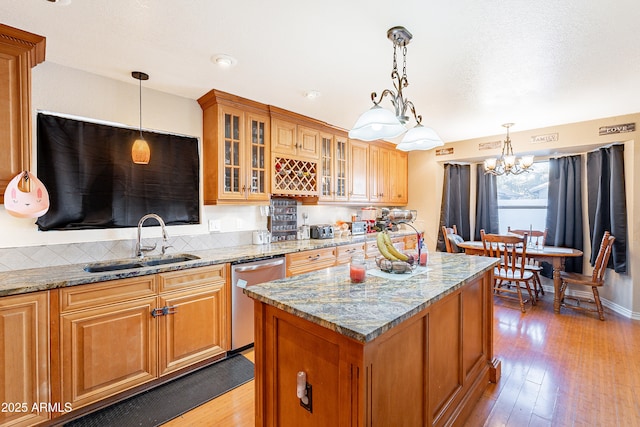 kitchen with dishwasher, light stone counters, hanging light fixtures, and sink