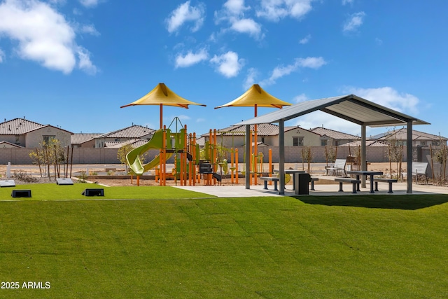 view of playground featuring a lawn, fence, and a residential view