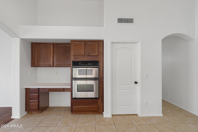 kitchen featuring stainless steel double oven and light tile patterned floors