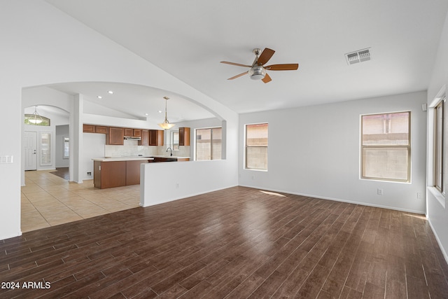 unfurnished living room with vaulted ceiling, ceiling fan, and sink