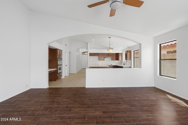 unfurnished living room with ceiling fan, sink, and vaulted ceiling