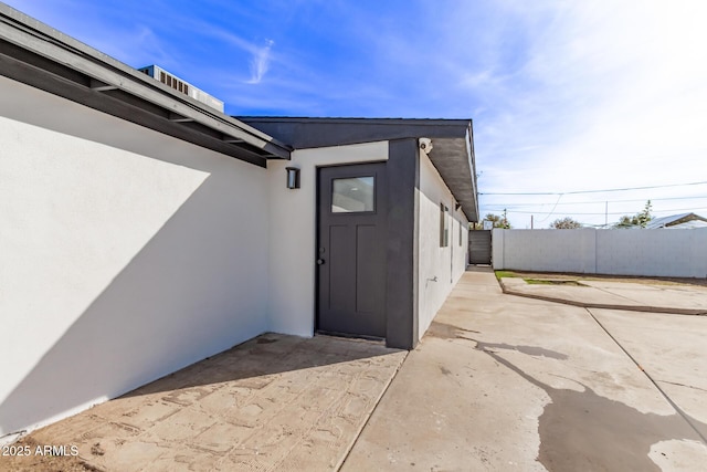 property entrance with a patio, fence, and stucco siding