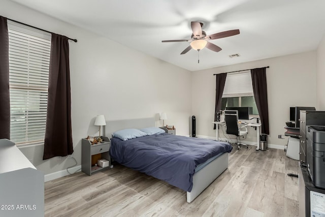 bedroom with ceiling fan, light wood-style floors, visible vents, and baseboards