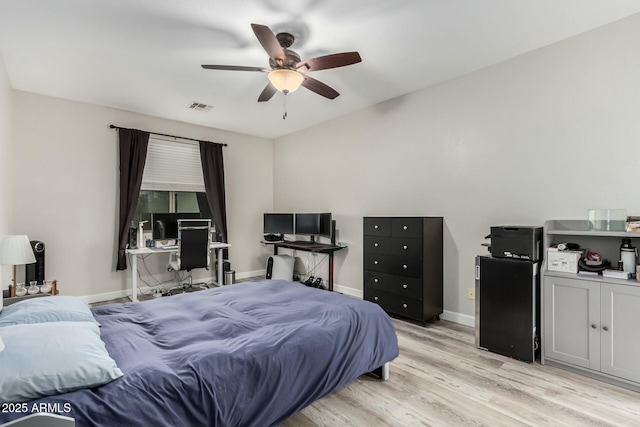 bedroom featuring baseboards, visible vents, light wood finished floors, and ceiling fan