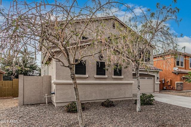 view of front of house featuring stucco siding, concrete driveway, a garage, and fence