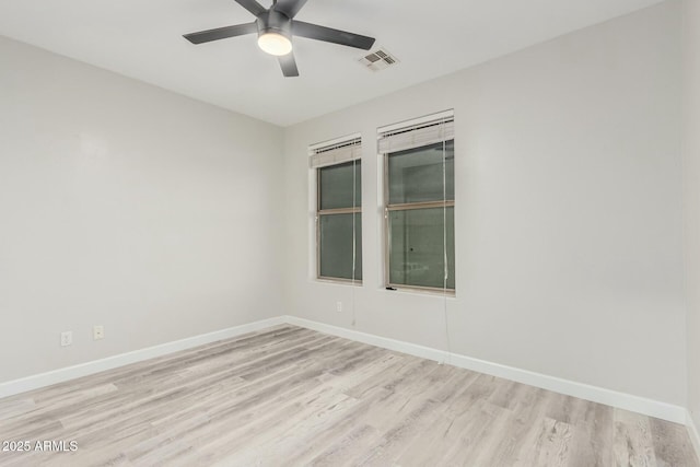 spare room featuring a ceiling fan, light wood-style flooring, baseboards, and visible vents