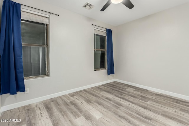 spare room featuring wood finished floors, a ceiling fan, visible vents, and baseboards