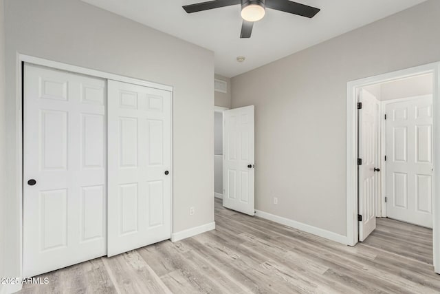 unfurnished bedroom with a closet, baseboards, light wood-style floors, and a ceiling fan