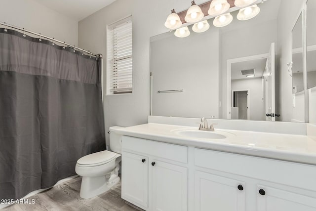 bathroom featuring visible vents, toilet, a shower with curtain, wood finished floors, and vanity