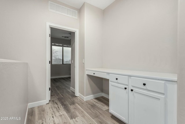 hallway featuring visible vents, baseboards, and light wood-style flooring