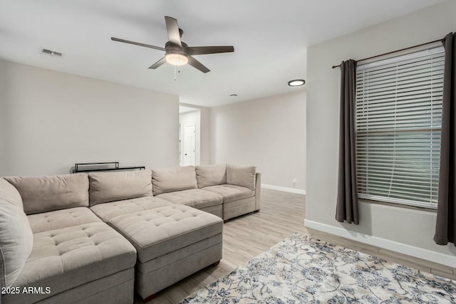 living room with visible vents, baseboards, light wood-style flooring, and a ceiling fan