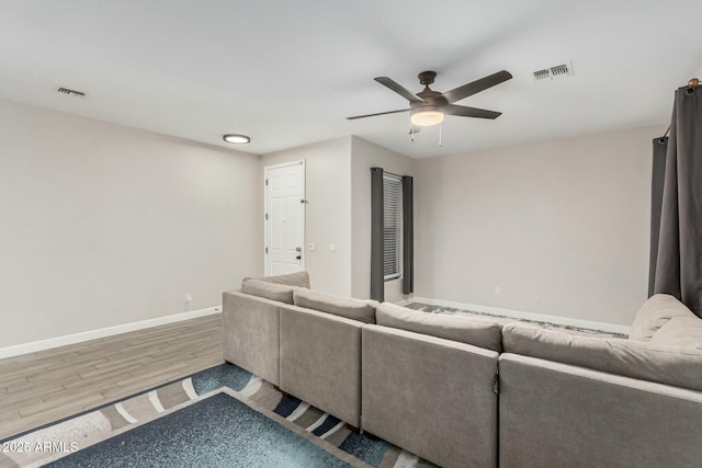 living area featuring wood finished floors, visible vents, baseboards, and ceiling fan