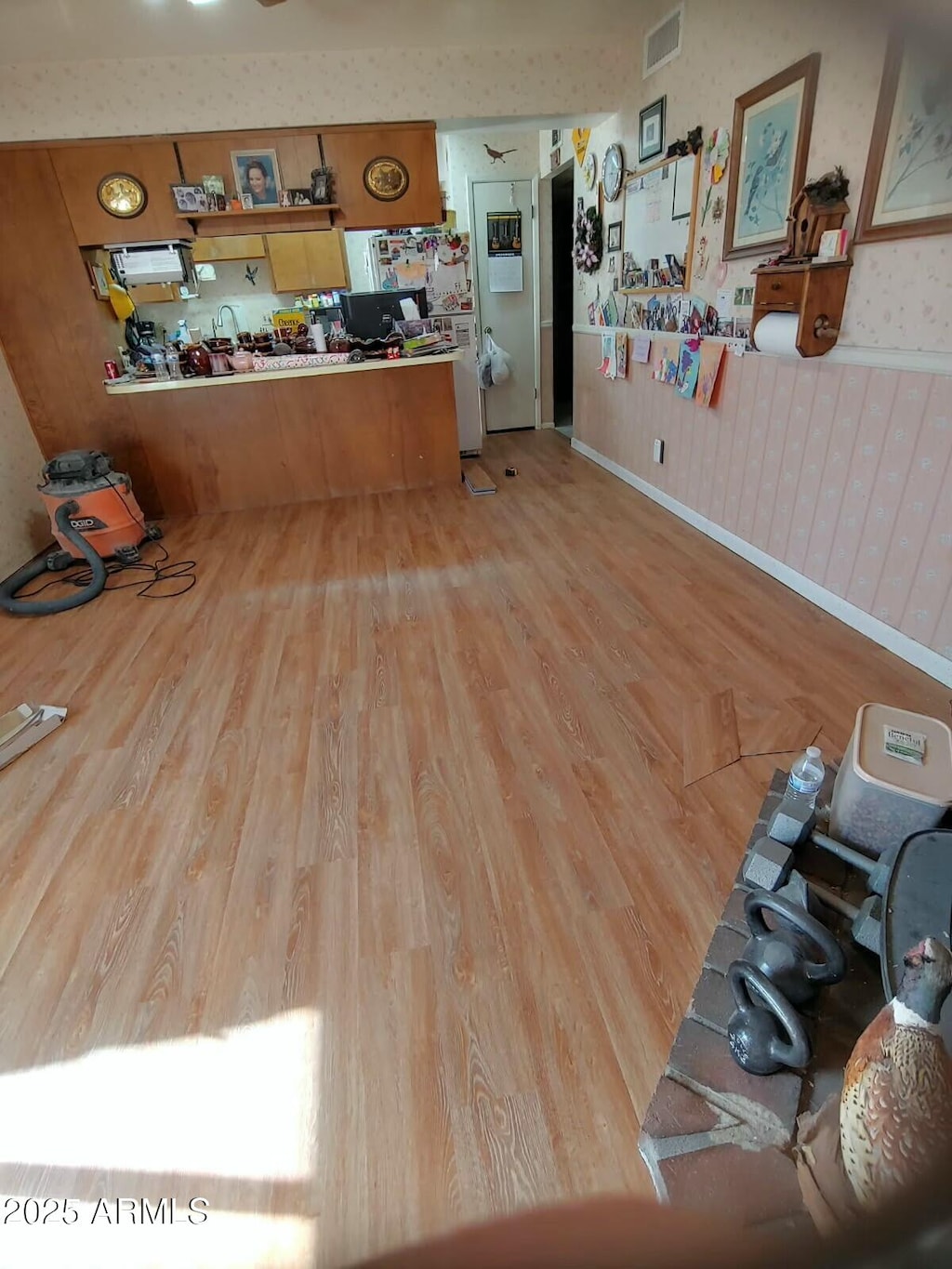 kitchen featuring wallpapered walls, wood finished floors, visible vents, and baseboards
