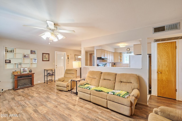 5410 E University Dr, Mesa, AZ 85205 - living room with light wood-style floors, a ceiling fan, and a glass covered fireplace
