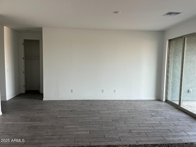 unfurnished room featuring visible vents, baseboards, and wood finished floors