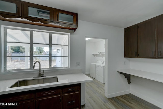 kitchen with sink, light wood-type flooring, dark brown cabinetry, and washing machine and clothes dryer