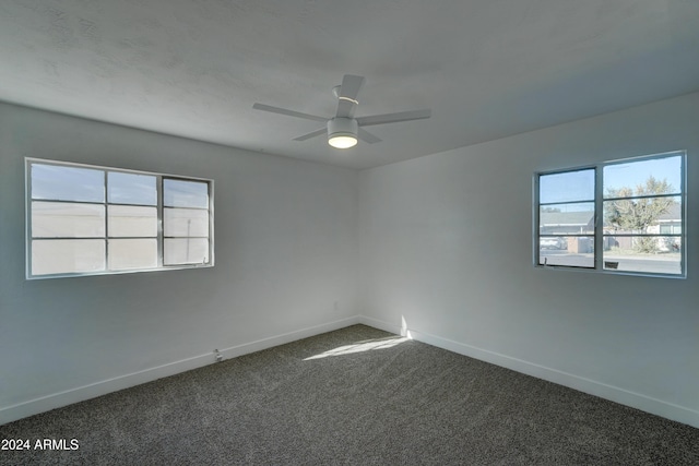 empty room with dark colored carpet and ceiling fan