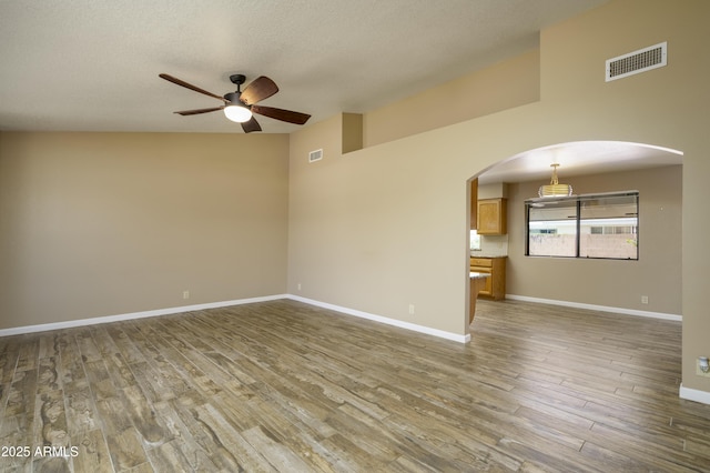 8230 E Navarro Ave, Mesa, AZ 85209 - empty room featuring a ceiling fan, wood finished floors, arched walkways, baseboards, and a textured ceiling