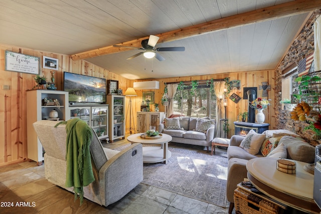 living room with wooden walls, a wealth of natural light, vaulted ceiling with beams, and ceiling fan