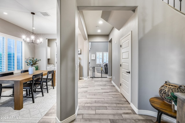 hall featuring light hardwood / wood-style floors, a notable chandelier, and plenty of natural light