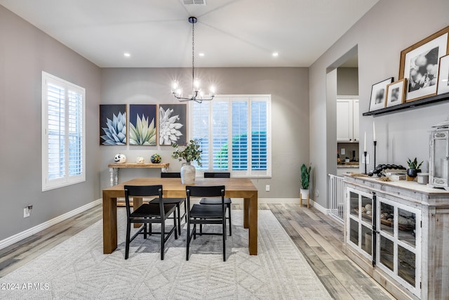 dining space featuring light hardwood / wood-style floors and a notable chandelier