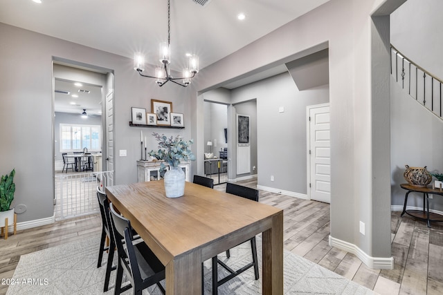 dining area with ceiling fan with notable chandelier and light hardwood / wood-style floors