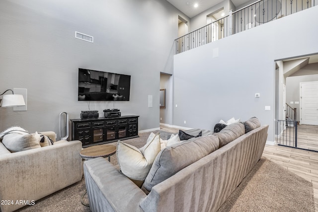 living room with a towering ceiling and light hardwood / wood-style flooring