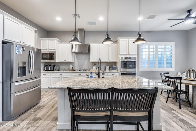 kitchen with light hardwood / wood-style flooring, stainless steel appliances, and a kitchen bar