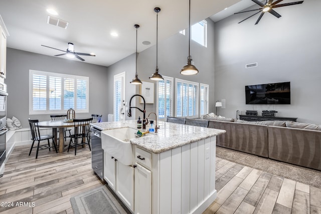 kitchen featuring white cabinetry, sink, a center island with sink, and pendant lighting