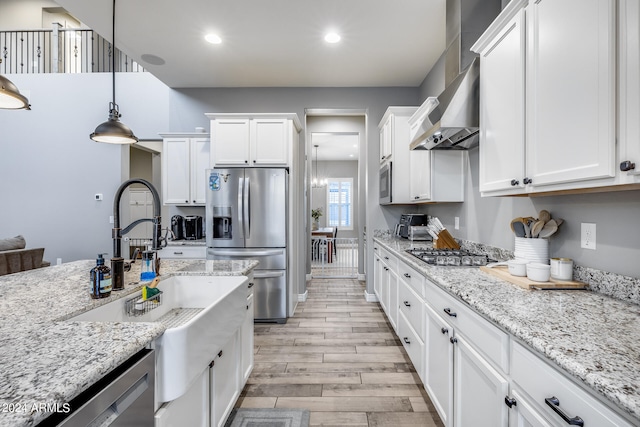 kitchen with white cabinets, light stone counters, light hardwood / wood-style flooring, pendant lighting, and stainless steel appliances