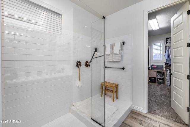 bathroom with a tile shower and hardwood / wood-style flooring