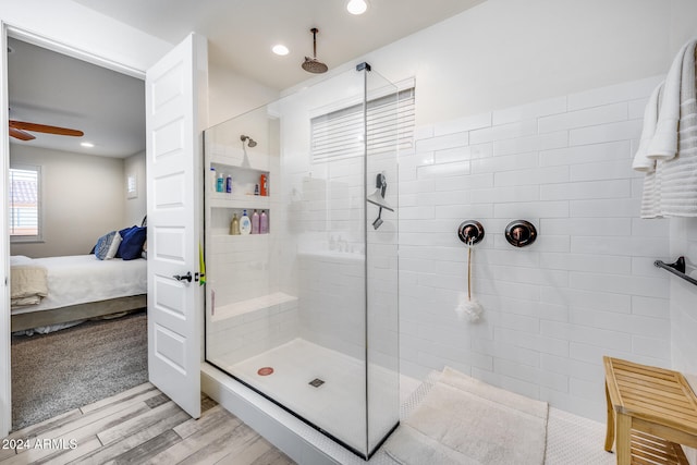 bathroom featuring ceiling fan, wood-type flooring, and tiled shower