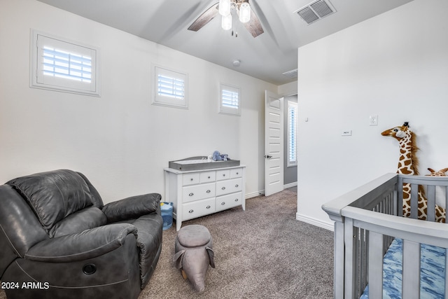 carpeted bedroom featuring a nursery area and ceiling fan