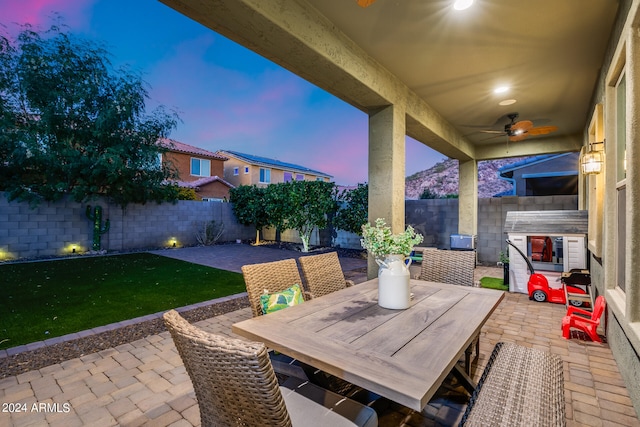 patio terrace at dusk with a yard and ceiling fan