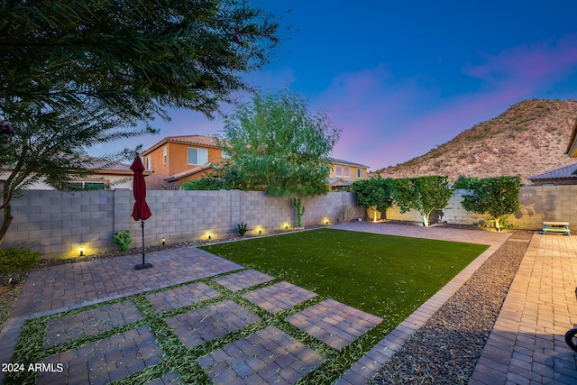 yard at dusk featuring a patio and a mountain view