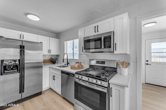 kitchen featuring light wood-style floors, a sink, appliances with stainless steel finishes, and light countertops