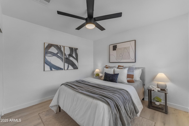 bedroom with baseboards, a ceiling fan, wood finished floors, and visible vents
