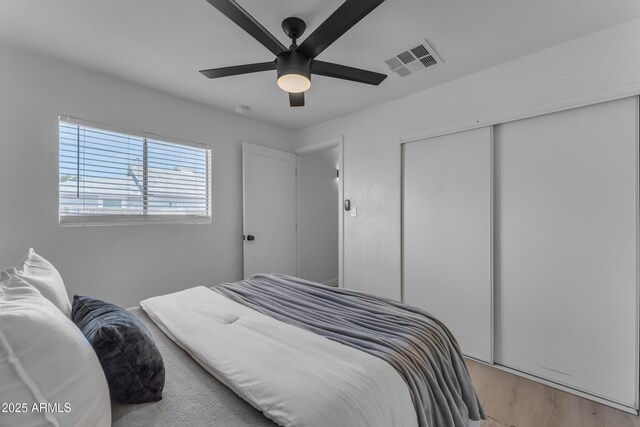 bedroom featuring visible vents, light wood finished floors, ceiling fan, and a closet
